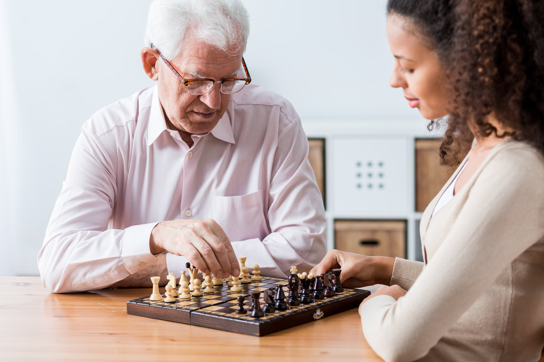 home care aide plays chess with senior at home