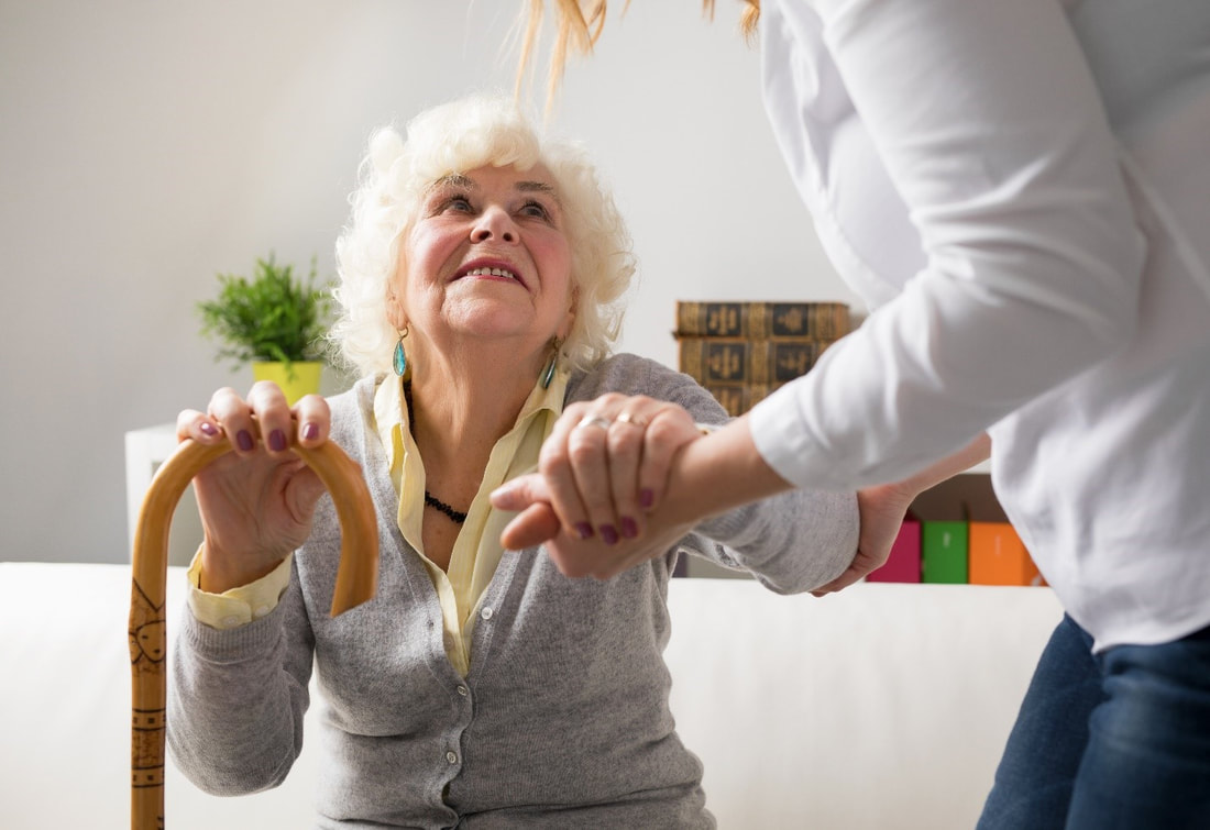home caregiver helping a senior woman get up