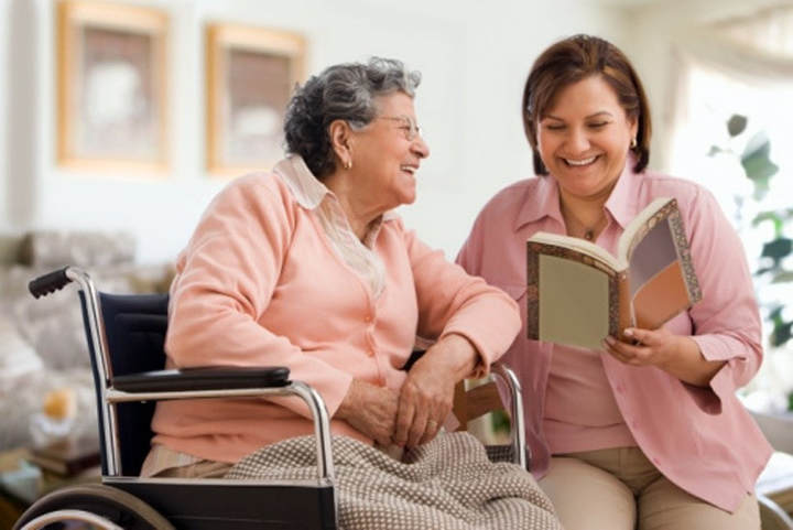 Home Caregiver reads to a senior living in Wellesley, MA